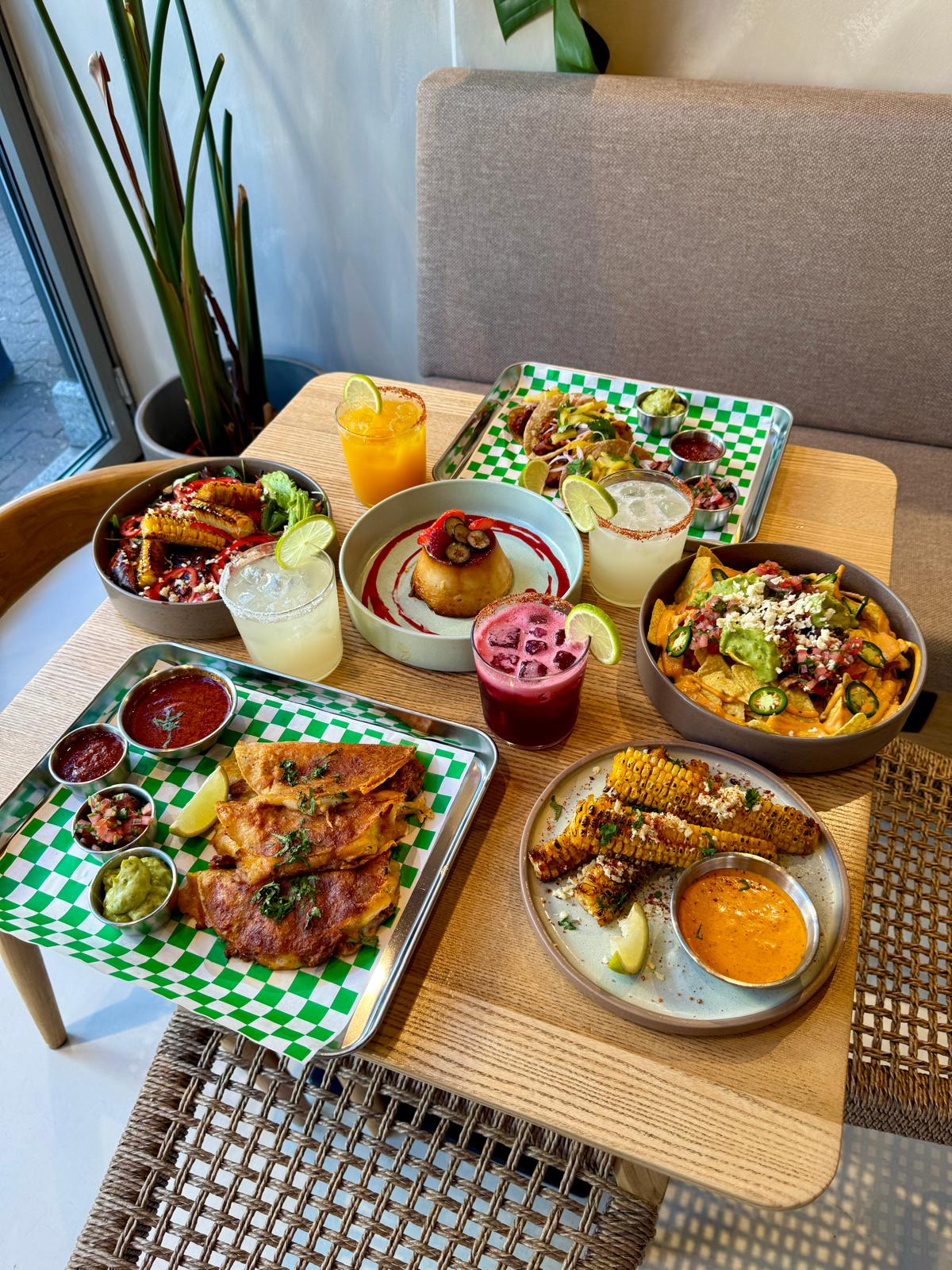 Mesa puesta con tacos, nachos, corn ribs y margaritas