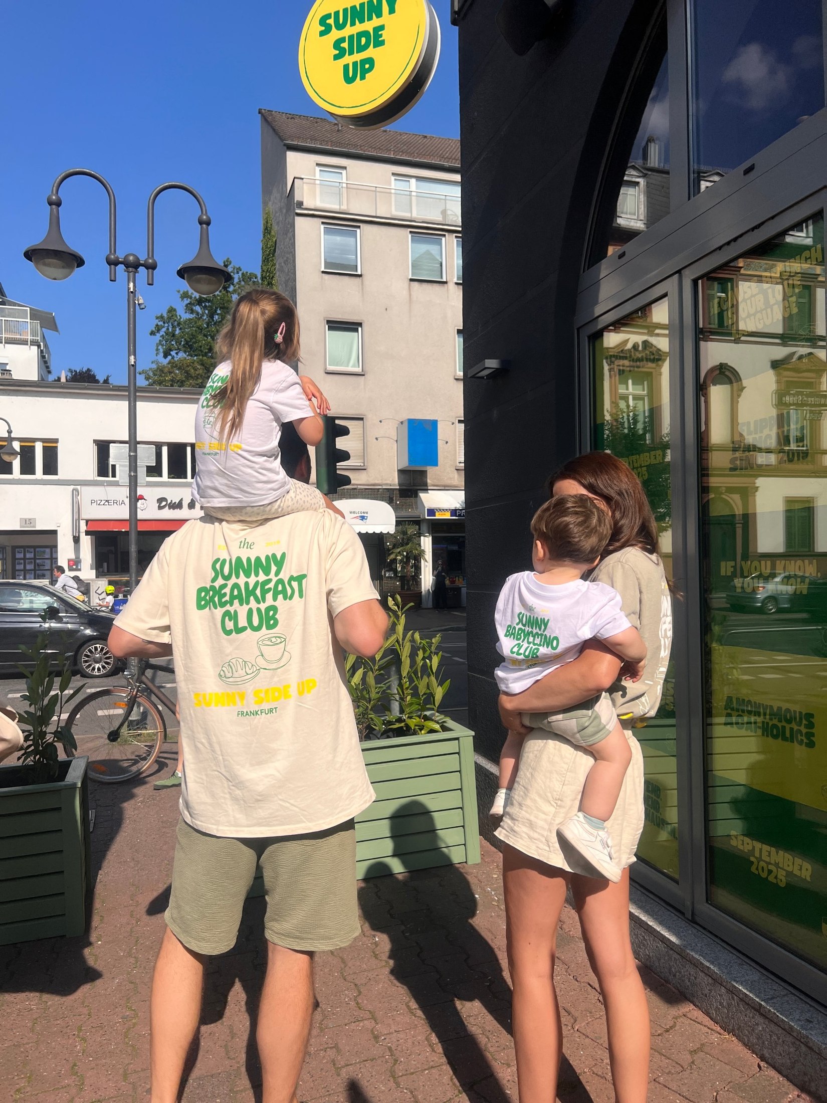 Familie mit Kindern auf den Schultern vor dem Sunny Side Up